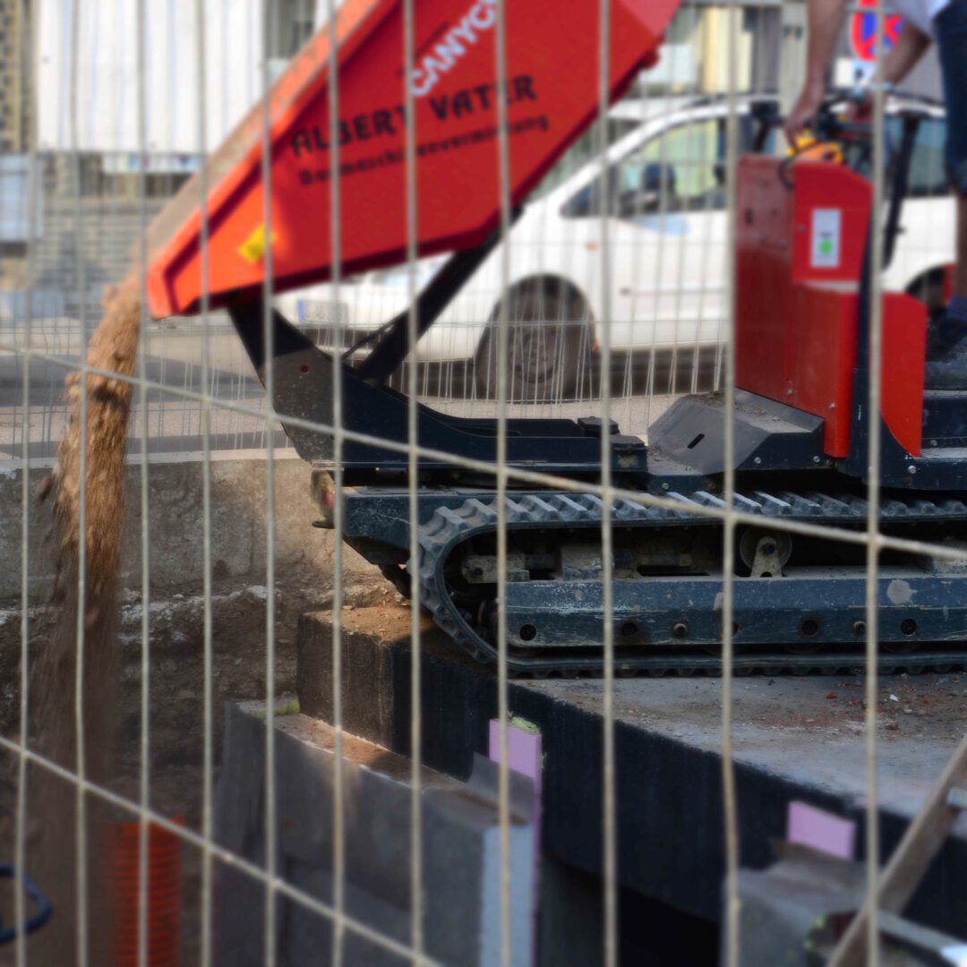 Bezahlbar Bauen. Das Bild zeigt einen kleinen Kipper, der den Arbeitsraum füllt.